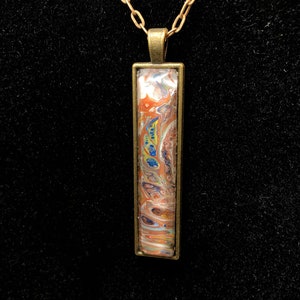 Abstract acrylic painting set in a long rectangular bronze tone pendant and hung on a matching chain N23