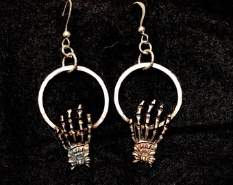 Sterling Silver skeletal hands hang from you ears.
