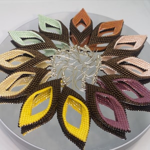 May include: A set of 10 pairs of beaded earrings in various colors, including brown, yellow, pink, and green. Each earring is shaped like a leaf with a cut-out design in the center.