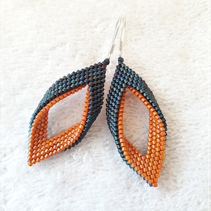 May include: A pair of dangle earrings with a twisted design. The earrings are made with orange and dark green beads.