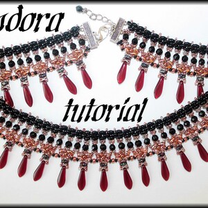 Op de afbeelding: Een zwarte en koperen kralenketting met rode traanvormige kralen die eronder hangen. De ketting heeft een zilveren sluiting en de tekst "Pandora tutorial" staat in het midden van de afbeelding.