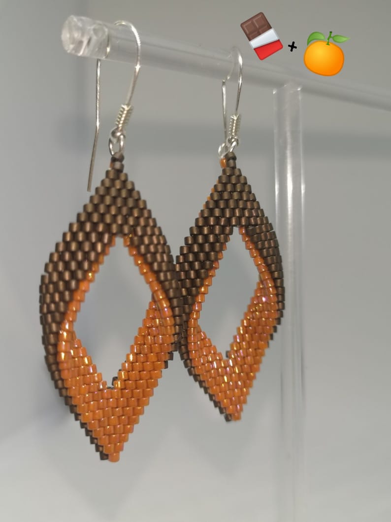 May include: A pair of dangle earrings with a diamond shape. The earrings are made of brown and orange beads.