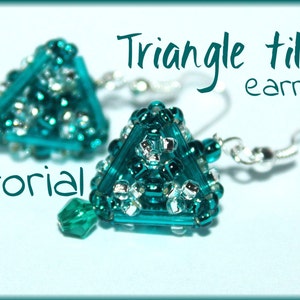 Op de afbeelding: Turquoise en zilveren driehoekige tegel oorbellen met kristal accenten. De oorbellen zijn op een lichtblauwe achtergrond. Tutorial voor driehoekige tegel oorbellen.