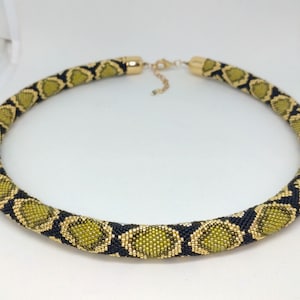 May include: A gold and black beaded necklace with a snake skin pattern.