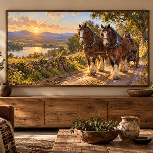 Puede incluir: Un cuadro de paisaje enmarcado que representa a dos caballos de tiro marrones tirando de un carro de madera con un conductor por un camino de tierra. La escena muestra una puesta de sol sobre un r&iacute;o, colinas y un muro de piedra.