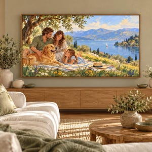 May include: A rectangular wall art print in a wooden frame depicting a family of three and a golden retriever sitting on a picnic blanket under an olive tree, overlooking a blue lake with distant mountains and a small sailboat on the water.