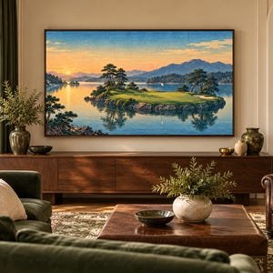 Puede incluir: Una gran obra de arte mural rectangular enmarcada que representa un paisaje sereno con una isla de campo de golf en el centro de un lago tranquilo, rodeada de monta&ntilde;as bajo un suave cielo de atardecer con tonos naranja y azul.