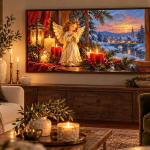 Puede incluir: Un cuadro rectangular que muestra una escena navide&ntilde;a con una figura de &aacute;ngel central, velas rojas y un farol. El fondo presenta un paisaje de pueblo nevado al atardecer, enmarcado por ramas de pino y bayas rojas, todo en un marco oscuro.