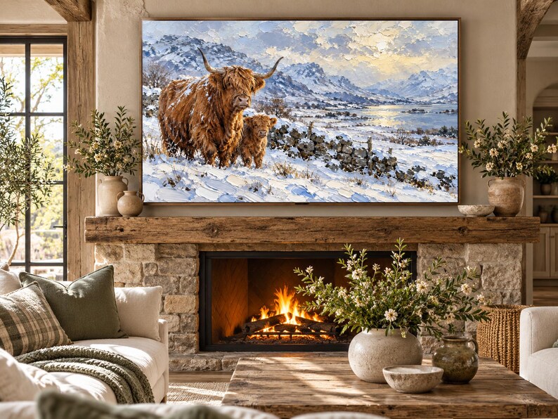 Puede incluir: Una impresi&oacute;n de arte mural rectangular que presenta una pintura al &oacute;leo de una vaca Highland marr&oacute;n peluda y un ternero en un paisaje nevado con monta&ntilde;as y un lago de fondo, exhibida sobre una chimenea de piedra con fuego encendido.