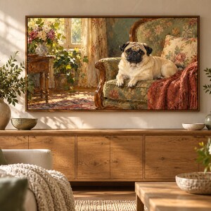 May include: A rectangular wall art print in a wooden frame depicting a fawn-colored pug resting on a floral patterned armchair. The scene includes a sunlit room with a wooden side table, a vase of flowers, and a draped rust-colored throw blanket.