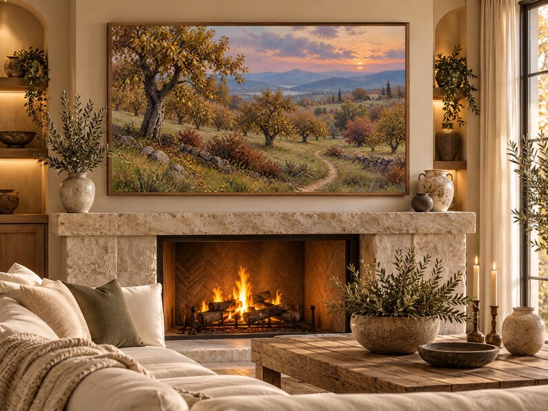 May include: A rectangular landscape painting in a thin brown frame depicting an orchard with golden-hued trees, a winding dirt path, and a stone wall under a sunset sky, mounted above a stone fireplace with a burning fire and a wooden coffee table.