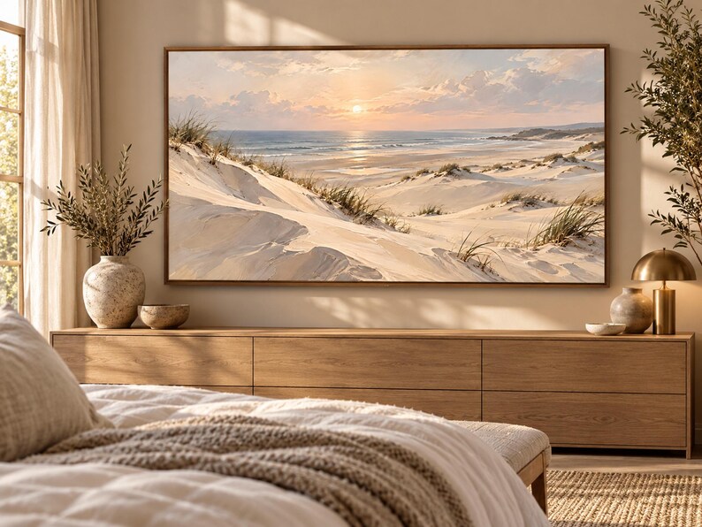 May include: A rectangular landscape wall art print featuring a coastal scene with white sand dunes, beach grass, and a calm ocean under a soft sunset sky. The artwork is framed in a thin wood border and displayed above a long wooden media console.