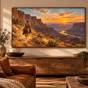 Puede incluir: Un cuadro rectangular de pared con un paisaje de un jinete solitario a caballo por un sendero des&eacute;rtico polvoriento. La escena muestra imponentes acantilados de roca roja, un r&iacute;o serpenteante y una puesta de sol vibrante con tonos naranjas.