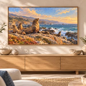 May include: A rectangular wall art print featuring a coastal landscape with several sea lions resting on rocky terrain. The scene depicts a blue ocean with crashing waves under a golden sunset sky, framed in a light-colored wooden border.