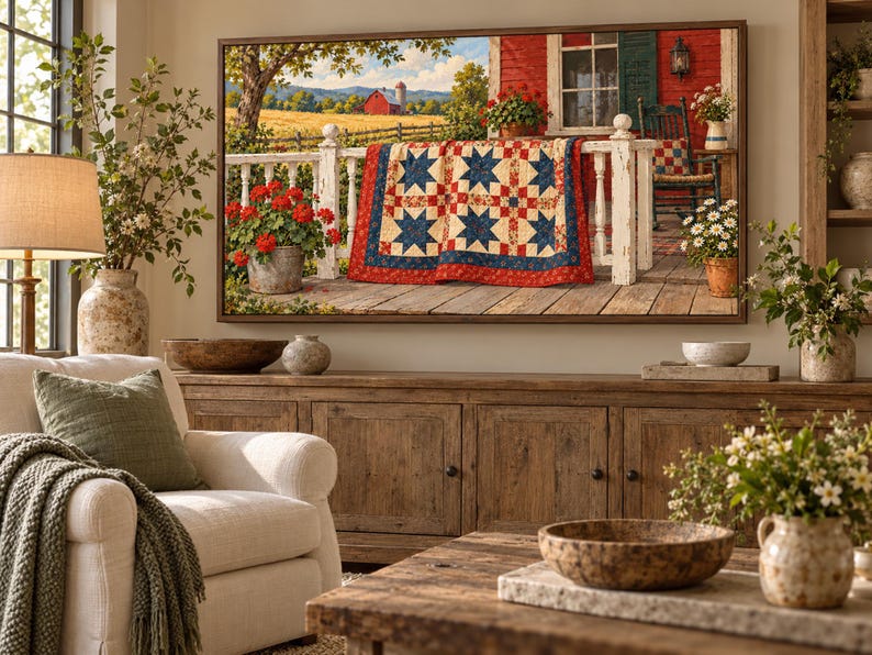 Puede incluir: Una impresi&oacute;n de arte mural rectangular que muestra una escena campestre con un granero rojo en un campo dorado, una barandilla de porche de madera blanca y una colcha con patr&oacute;n de estrellas en rojo, blanco y azul, en un marco de madera.