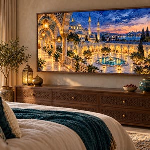 May include: A rectangular wall art print featuring a detailed architectural scene of a mosque with arched stone walkways, glowing lanterns, and a central fountain at sunset, displayed in a thin wooden frame above a dark wood media console.