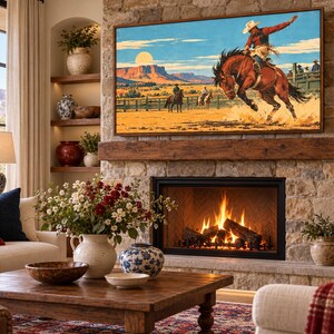 May include: A rectangular wall art print featuring a vibrant illustration of a cowboy riding a bucking brown horse in a desert landscape with mesas and a full moon, displayed in a dark wooden frame above a stone fireplace in a living room.