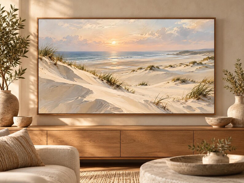 May include: A rectangular landscape wall art print featuring a coastal scene with rolling sand dunes, patches of green beach grass, and a calm ocean under a soft sunset sky with light clouds, all enclosed within a thin, natural wood-toned frame.
