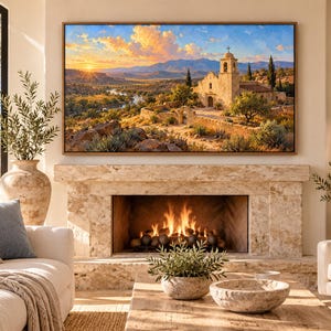 May include: A rectangular wall art print featuring a landscape painting of a stone mission church at sunset, with golden light illuminating the mountains, a winding river, and desert vegetation, framed in a thin brown wooden border.