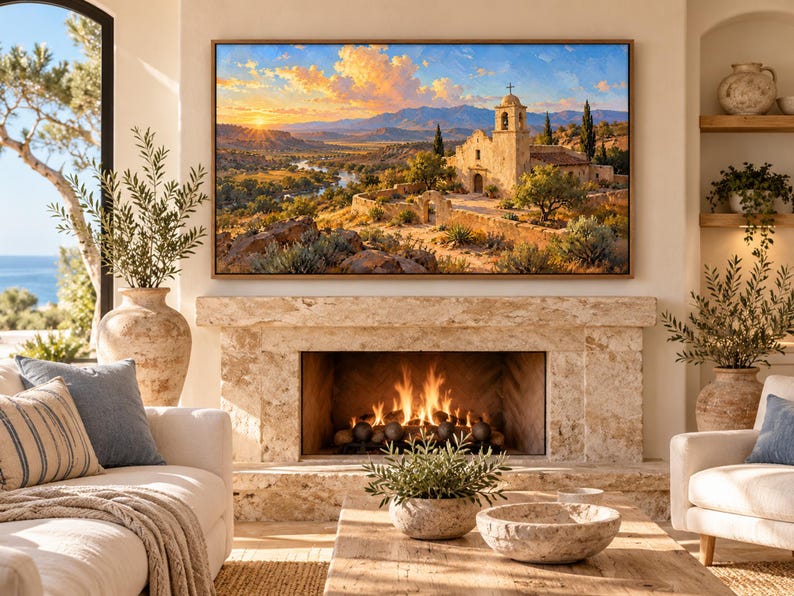 May include: A rectangular wall art print featuring a landscape painting of a stone mission church at sunset, with golden light illuminating the mountains, a winding river, and desert vegetation, framed in a thin brown wooden border.