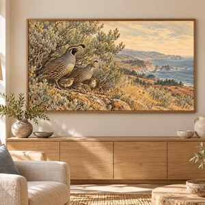May include: A rectangular framed wall art print featuring a detailed illustration of a family of California quail perched on a rocky hillside overlooking a coastal landscape with a blue ocean, golden cliffs, and a soft, hazy sky.
