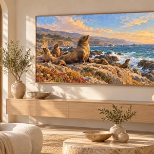 May include: A rectangular wall art print featuring a coastal scene with several brown sea lions resting on rocky cliffs above a turquoise ocean. The sky is filled with soft orange and blue clouds during sunset, framed by a thin wooden border.