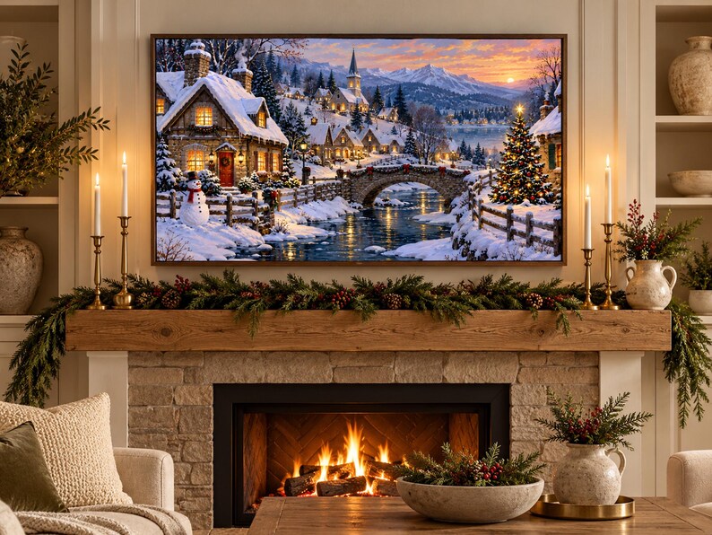 May include: A rectangular wall art print depicting a snowy winter village scene with stone cottages, a stone bridge over a river, a snowman, and a lit Christmas tree under a sunset sky, mounted above a fireplace with a wooden mantel and greenery.