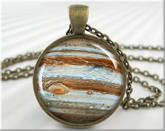 May include: A bronze chain necklace with a round pendant featuring a detailed image of Jupiter, the largest planet in our solar system. The pendant has a glass dome with a printed image of Jupiter's swirling clouds and brown bands.