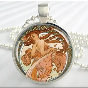 May include: A silver necklace with a round pendant featuring a colorful Art Nouveau illustration of a woman with flowing hair and a floral design. The pendant is surrounded by a decorative border.
