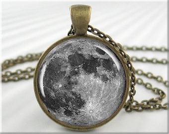 May include: A silver chain necklace with a round pendant featuring a black and white image of the moon.