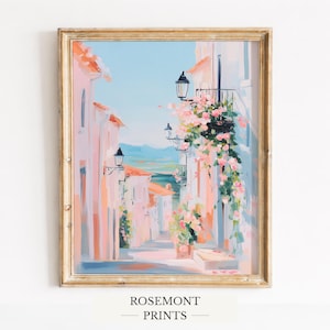 May include: A framed art print of a European street scene. The painting depicts a narrow alleyway with buildings in shades of pink and white, adorned with pink flowers. The sky is a light blue. The frame is gold. The text "ROSEMONT PRINTS" is at the bottom.
