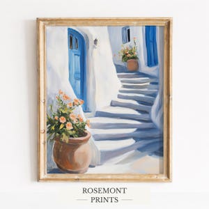 Puede incluir: Impresión artística enmarcada que representa una escena mediterránea soleada. Una puerta y una ventana azules contrastan con paredes blancas. Macetas de terracota con plantas florecientes. El texto "ROSEMONT PRINTS" está en la parte inferior.