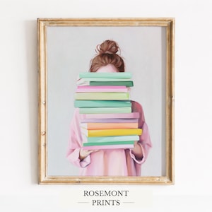 Op de afbeelding: Een ingelijste kunstdruk met een persoon die een stapel kleurrijke boeken vasthoudt. Het gezicht van de persoon wordt gedeeltelijk bedekt door de boeken. De print heeft een goudkleurige lijst en de tekst "ROSEMONT PRINTS" onderaan.