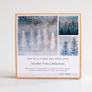 May include: A box of 12 winter tree themed greeting cards and envelopes. The box features a collage of three different designs, each depicting a snowy forest scene with white and blue trees. The text on the box reads "BOX OF 12 CARDS AND ENVELOPES Winter Trees Collection".