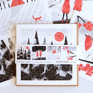 May include: Set of four blank greeting cards featuring winter scenes in black, white, and red. The cards feature a snowy forest, a red robin, a red sun, and a red house. The text on the cards reads "4 Blank Cards // Snowfall Collection // Ruth Thorp Studio".