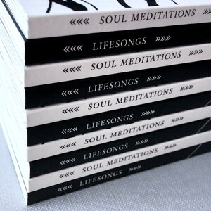 May include: A stack of books with black and white covers. The covers have the text "Soul Meditations" and "Lifesongs" repeated on each book.