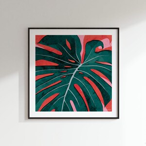 May include: A framed print of a large green monstera leaf with red and pink watercolor accents.