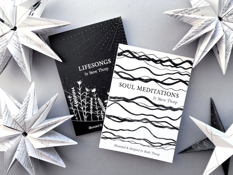 May include: Two black and white illustrated books titled "Lifesongs by Steve Thorp" and "Soul Meditations by Steve Thorp". The books are on a gray surface with white paper stars.