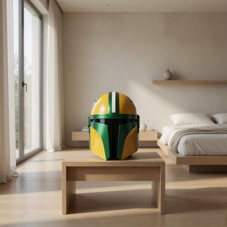 Pu&ograve; includere: Un casco Mandaloriano giallo, verde e bianco &egrave; appoggiato su un tavolo di legno. Il casco ha una cupola gialla con due strisce bianche e dettagli verdi. &Egrave; una replica del casco indossato dal personaggio del franchise di Star Wars.