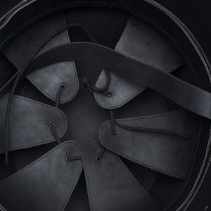 May include: The interior of a black helmet featuring a suspension liner made of six triangular leather flaps. These flaps are connected by thin black cords that lace through eyelets at the top, creating an adjustable fit system inside the shell.