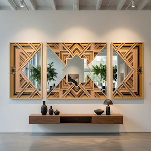 May include: A triptych of wall mirrors featuring intricate, layered geometric wooden frames in shades of tan, brown, and mustard yellow. Below the mirrors, a long, floating wooden console shelf holds three black vases, a bowl, and a lamp.