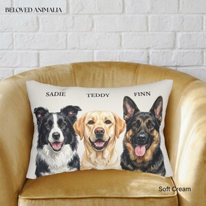 May include: A rectangular throw pillow featuring illustrations of three dogs: a black and white Border Collie, a yellow Labrador, and a German Shepherd. The names SADIE, TEDDY, and FINN are printed above each dog, with BELOVED ANIMALIA at the top.