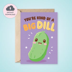 Peut inclure: Carte de vœux avec un fond violet et une illustration de cornichon de dessin animé. Le texte "YOU'RE KIND OF A BIG DILL" est écrit en marron et jaune. La carte est dans une enveloppe marron.