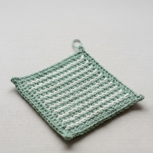 May include: A square, hand-crocheted potholder in a light green and white striped pattern. The potholder has a loop for hanging and is made of a soft, textured yarn. The stitches are tight and even, creating a durable and heat-resistant kitchen accessory.