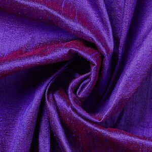 May include: Close-up of a deep purple fabric with a shimmering, textured surface. The fabric is folded, revealing darker shades of purple and red in the creases. The text "MYSTIC MIDNIGHT" is at the top.