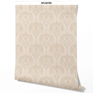 May include: A roll of wallpaper featuring a repeating damask pattern in shades of beige and cream. The design includes intricate swirling lines and organic shapes. The word SPLINTER is printed in black capital letters at the top of the roll.