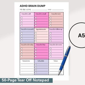 May include: A5-sized notepad with a grid layout for task organization, featuring sections like "I need to call," "I need to email," and "I need to do today." A blue pen rests on the page. The notepad is labeled "ADHD BRAIN DUMP" and "50-Page Tear Off Notepad."