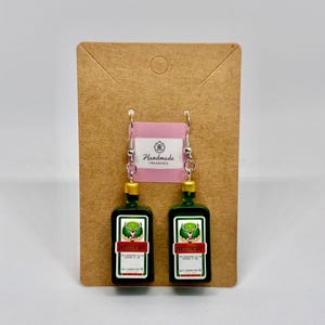 Könnte beinhalten: Weißer Keramikbecher mit schwarzem Henkel und dem Schriftzug "But First, Coffee" in handschriftlichem Stil. Der Becher fasst etwa 325-440 ml, ideal für Kaffee.