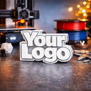 Op de afbeelding: Een wit en grijs 3D-geprint "Your Logo"-bord, met een 3D-printer en filamentspoelen op de achtergrond. Het bord is het middelpunt, met een getextureerd oppervlak en een schaduweffect.