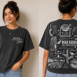 May include: Dark gray t-shirt with the text "The last of the bugs" on the front. The back of the shirt features a detailed white graphic design with the text "NOAH KAHAN THE GREAT DIVIDE" and other illustrations.